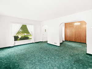 Empty room with a chandelier and dark colored carpet