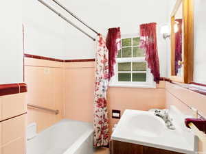 Bathroom featuring shower / bath combination with curtain, vanity, and tile walls