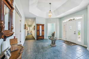 Entrance foyer with dark tile flooring and a tray ceiling