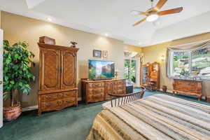 Bedroom with dark carpet, ceiling fan, and a tray ceiling