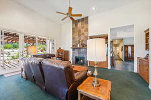 Living room featuring high vaulted ceiling, a fireplace, carpet floors, and ceiling fan