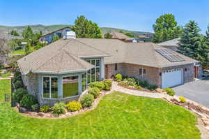 Single story home featuring a garage, a front lawn, and solar panels