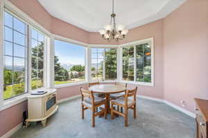 Dining space with a wealth of natural light, an inviting chandelier, and carpet flooring