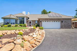 Single story home with a garage, a front yard, and solar panels