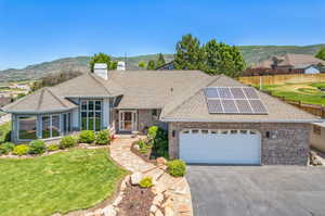 Single story home featuring a front lawn, a garage, a mountain view, and solar panels