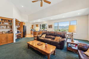 Living room with a towering ceiling, carpet, and ceiling fan