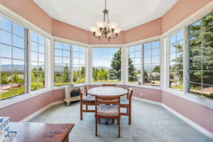 Sunroom with an inviting chandelier and a raised ceiling