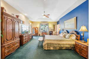 Bedroom featuring dark carpet, ceiling fan, and a raised ceiling