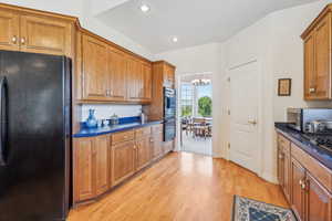 Kitchen with black appliances, a chandelier, and light hardwood / wood-style floors