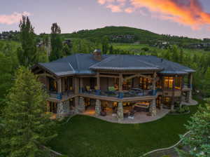 Back house at dusk featuring a yard and a patio