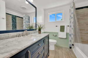 Full bathroom featuring tile floors, large vanity, toilet, and shower / bath combo with shower curtain