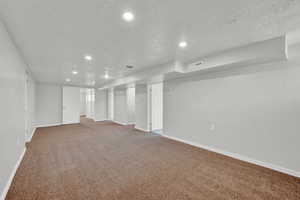 Basement with a textured ceiling and carpet floors