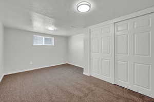 Interior space with a textured ceiling, a closet, and dark colored carpet