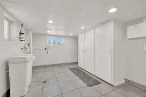 Laundry room with a textured ceiling and light tile flooring