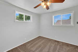 Bedroom with a wealth of natural light, ornamental molding, carpet, and ceiling fan