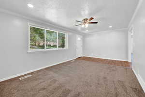 Living room with a textured ceiling, ceiling fan, carpet floors, and crown molding