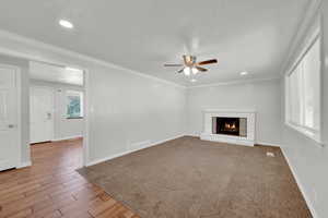 Living room with carpet, ceiling fan, crown molding, and a brick fireplace