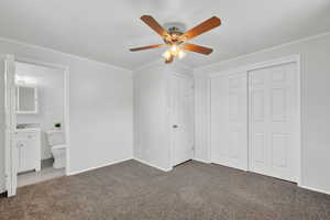 Bedroom with ensuite bath, ceiling fan, a closet, and dark carpet