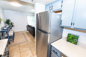 Kitchen with stainless steel refrigerator and light tile floors