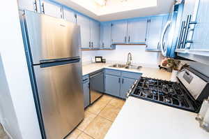 Kitchen featuring stainless steel appliances, grey cabinetry, sink, and light tile floors