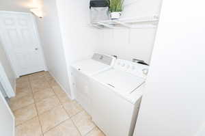 Clothes washing area with washing machine and clothes dryer and light tile flooring