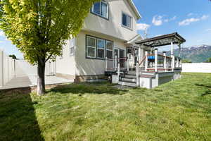 Back of house with a wooden deck and a lawn