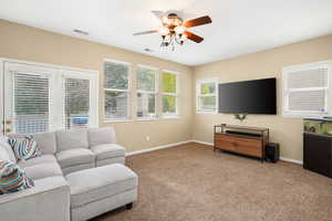 Carpeted living room featuring ceiling fan