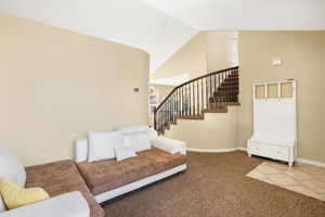 Carpeted living room featuring high vaulted ceiling