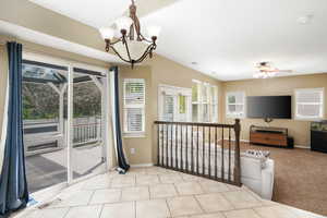 Interior space featuring light tile floors and ceiling fan with notable chandelier