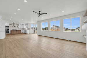 Unfurnished living room with ceiling fan and light wood-type flooring