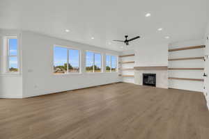 Unfurnished living room featuring ceiling fan, light hardwood / wood-style flooring, and a tiled fireplace