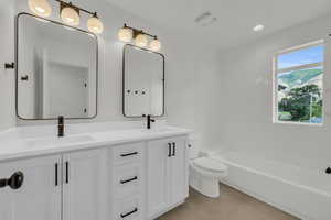 Full bathroom with tile patterned flooring, toilet, tiled shower / bath combo, and vanity