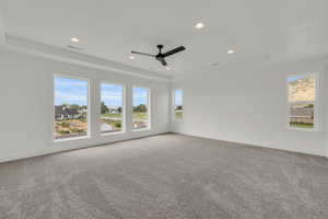 Spare room with ceiling fan, a tray ceiling, and carpet