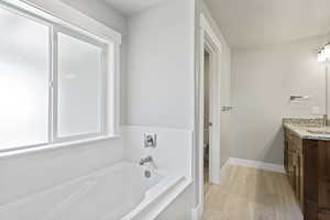 Bathroom with a bath to relax in, tile flooring, vanity, and toilet