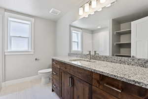 Bathroom with vanity with extensive cabinet space, tile flooring, and toilet