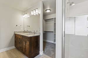 Bathroom with tile floors, a shower with shower door, and vanity