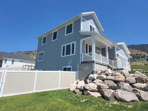 Rear view of house featuring a garage, a yard, a mountain view, and covered porch