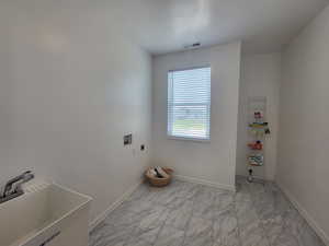 Laundry room with electric dryer hookup, sink, and light tile floors