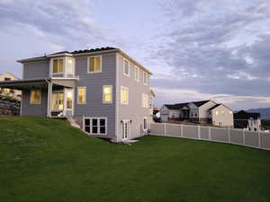 Back house at dusk featuring a yard