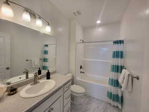 Full bathroom with tile floors, shower / tub combo, toilet, and vanity