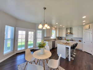 Dining area with a healthy amount of sunlight, a notable chandelier, and dark hardwood / wood-style flooring