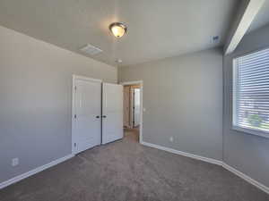 Unfurnished bedroom featuring a textured ceiling and carpet floors