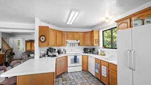 Kitchen featuring kitchen peninsula, a breakfast bar area, sink, white appliances, and light tile floors