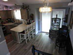 Kitchen featuring a breakfast bar area, hanging light fixtures, sink, and dark hardwood / wood-style floors