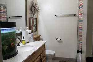 Full bathroom featuring shower / bath combo with shower curtain, toilet, and vanity