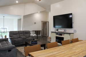 Living room featuring a notable chandelier, wood-type flooring, and high vaulted ceiling