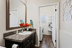 Bathroom featuring washer and dryer, wood-type flooring, and vanity