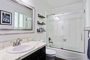 Full bathroom featuring shower / bath combination with glass door, vanity, toilet, and wood-type flooring