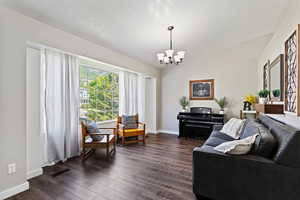 Living room with an inviting chandelier, a textured ceiling, and dark wood-type flooring