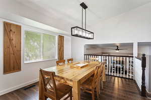 Dining area with vaulted ceiling, dark hardwood / wood-style flooring, and ceiling fan with notable chandelier